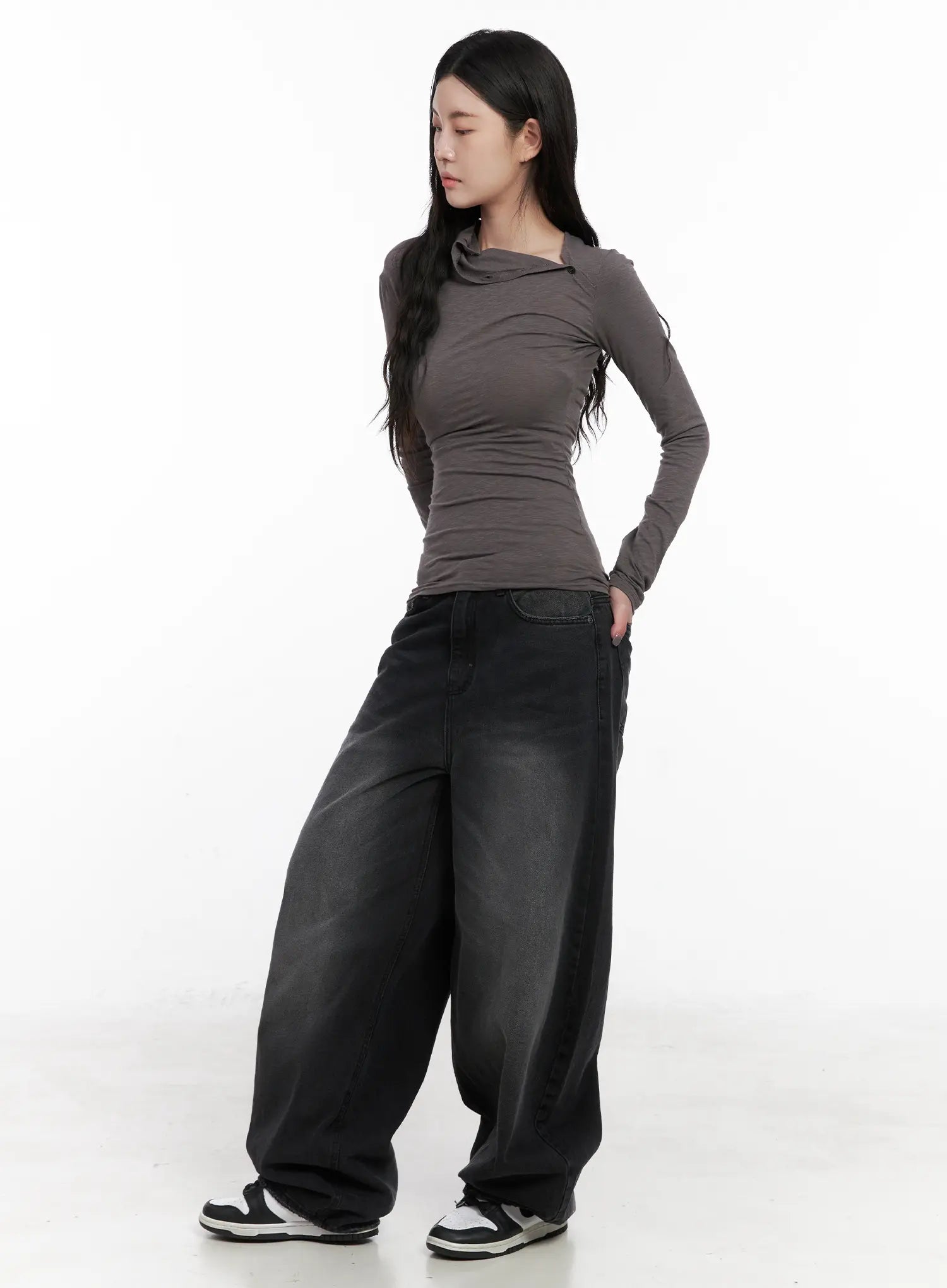 Yuji Dark-Washed Baggy Jeans CN513 in black, three-quarter front shot on model, wide-fit dark-washed cotton denim with hand in back pocket, paired with gray draped top and white sneakers.