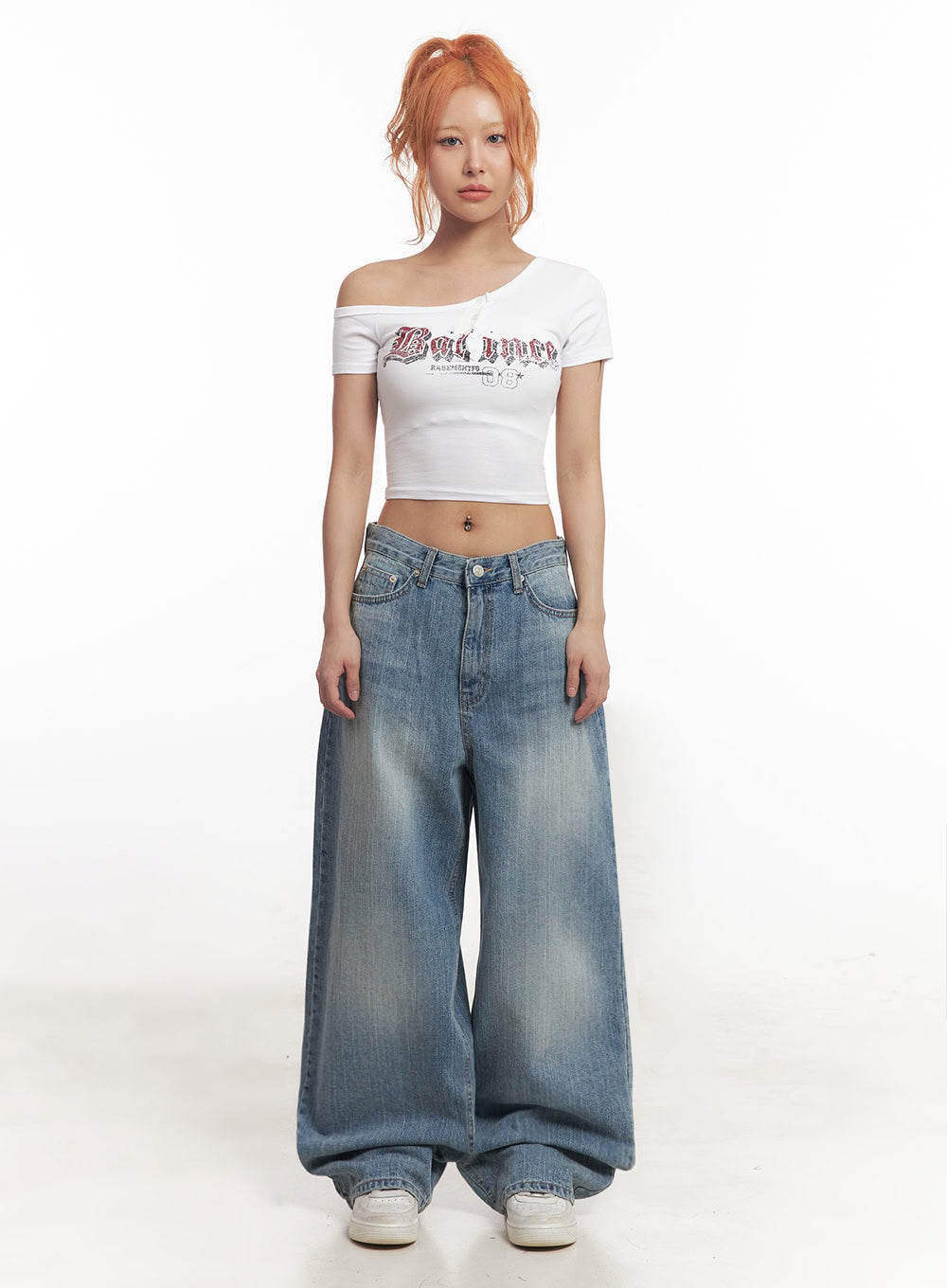 Yvette Washed Baggy Jeans IA517 in light blue, front full-body shot on model, exaggerated wide leg pooling at hem, washed cotton denim, paired with white asymmetric crop top and white sneakers.
