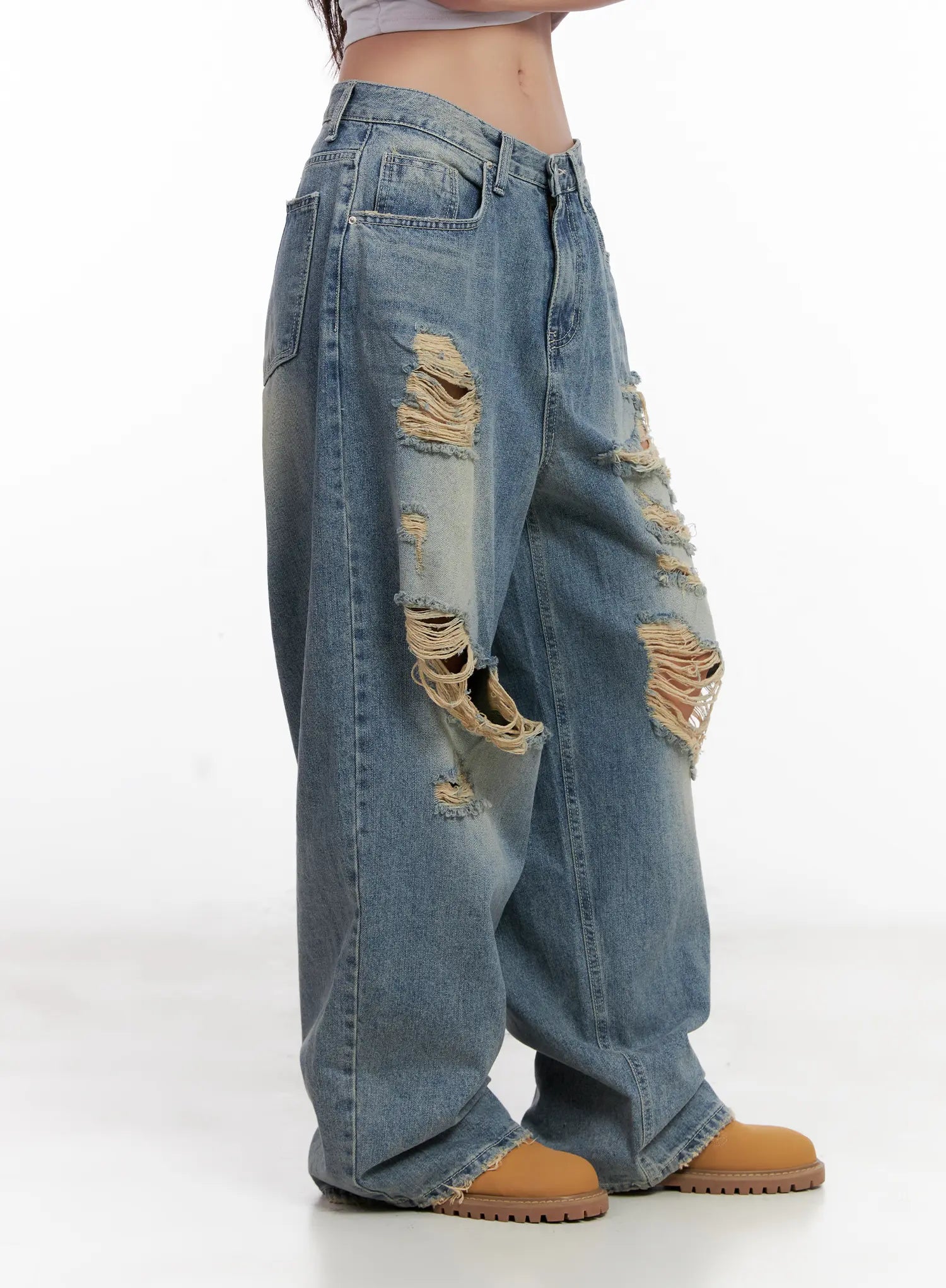 Manon Washed Distressed Wide Jeans CL518 in blue, side view on model, showing distressed rips along outer thigh, wide-leg sweep, and raw frayed hem at ankle.