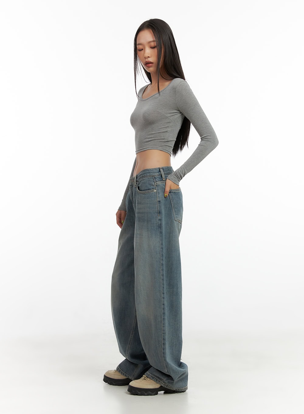 Nadia Washed Low-Waist Baggy Jeans CO424 in blue, full-body side shot on model, three-quarter angle highlighting wide baggy leg length pooling at hem, styled with grey crop top and chunky sneakers.