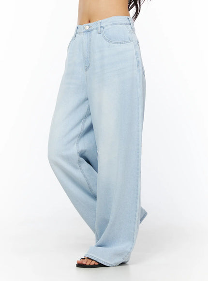 Rina Washed Wide-Leg Jeans CU522 in light blue, side view on model (waist-down), showing wide-leg drape and washed fade, paired with black sandals.