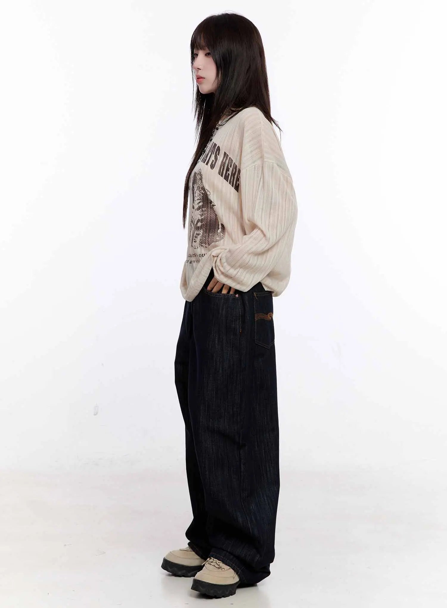 Haewon Dark Washed Baggy Jeans CS530 in dark blue, full-body side view on model, paired with cream ribbed graphic top and chunky sneakers, oversized wide-leg length puddling at hem.