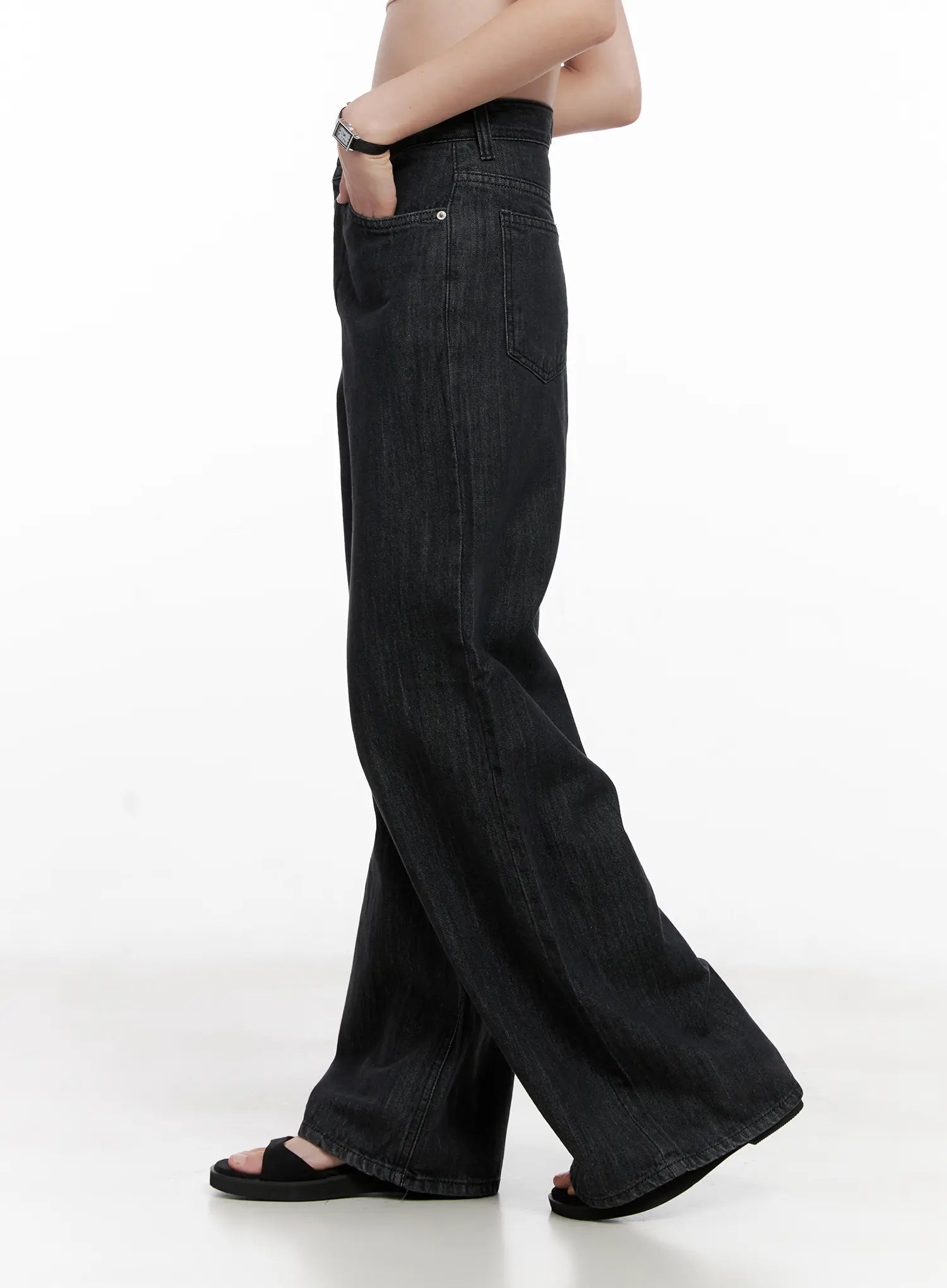 Yeon High-Waist Wide Jeans CL523 in black, side view on model, high-waist silhouette with clean side seam, wide flared leg pooling at sandals, hand in pocket.