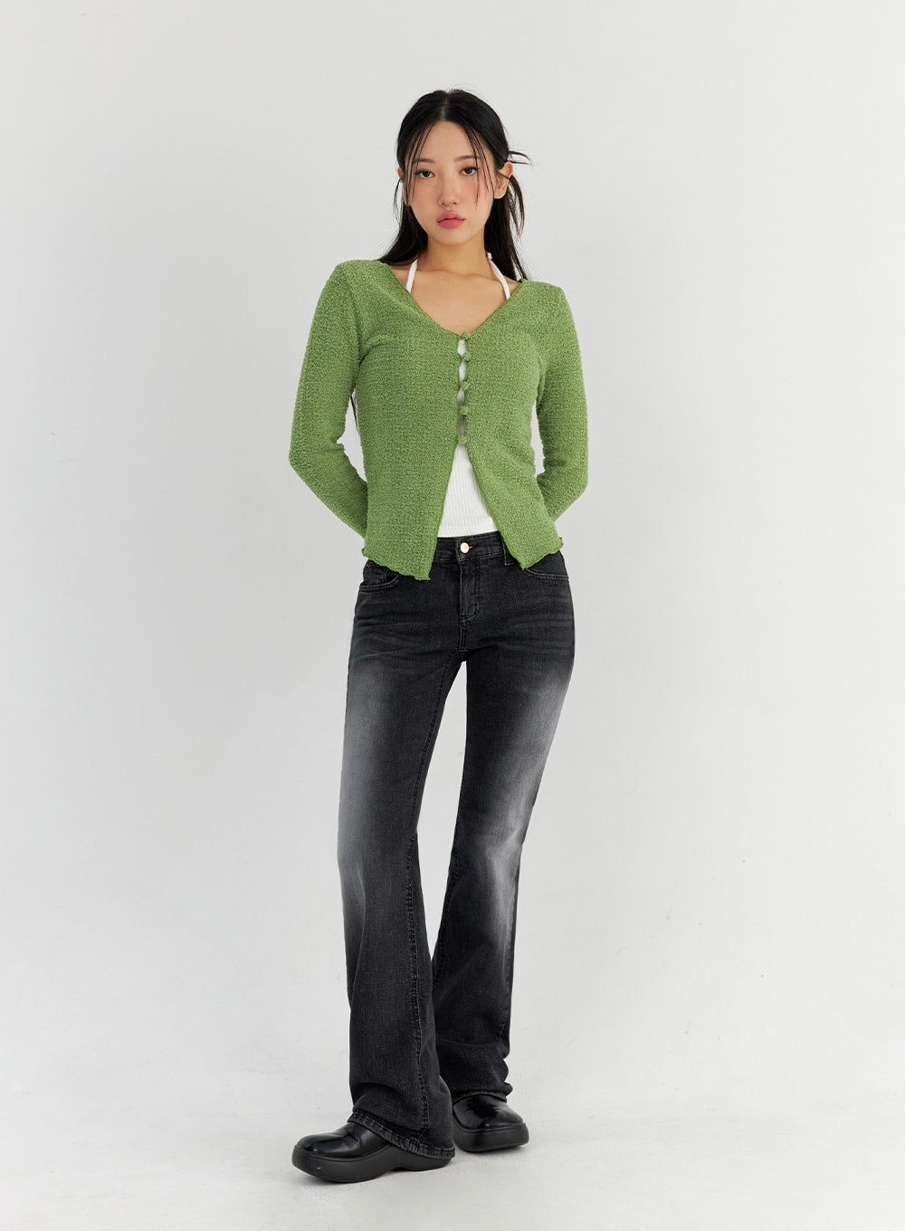 Bootcut Washed Jeans CO325 in dark gray, full-body slight side view on model, washed denim with subtle fade, slim fit through thigh flaring to bootcut hem, paired with green bouclé cardigan.