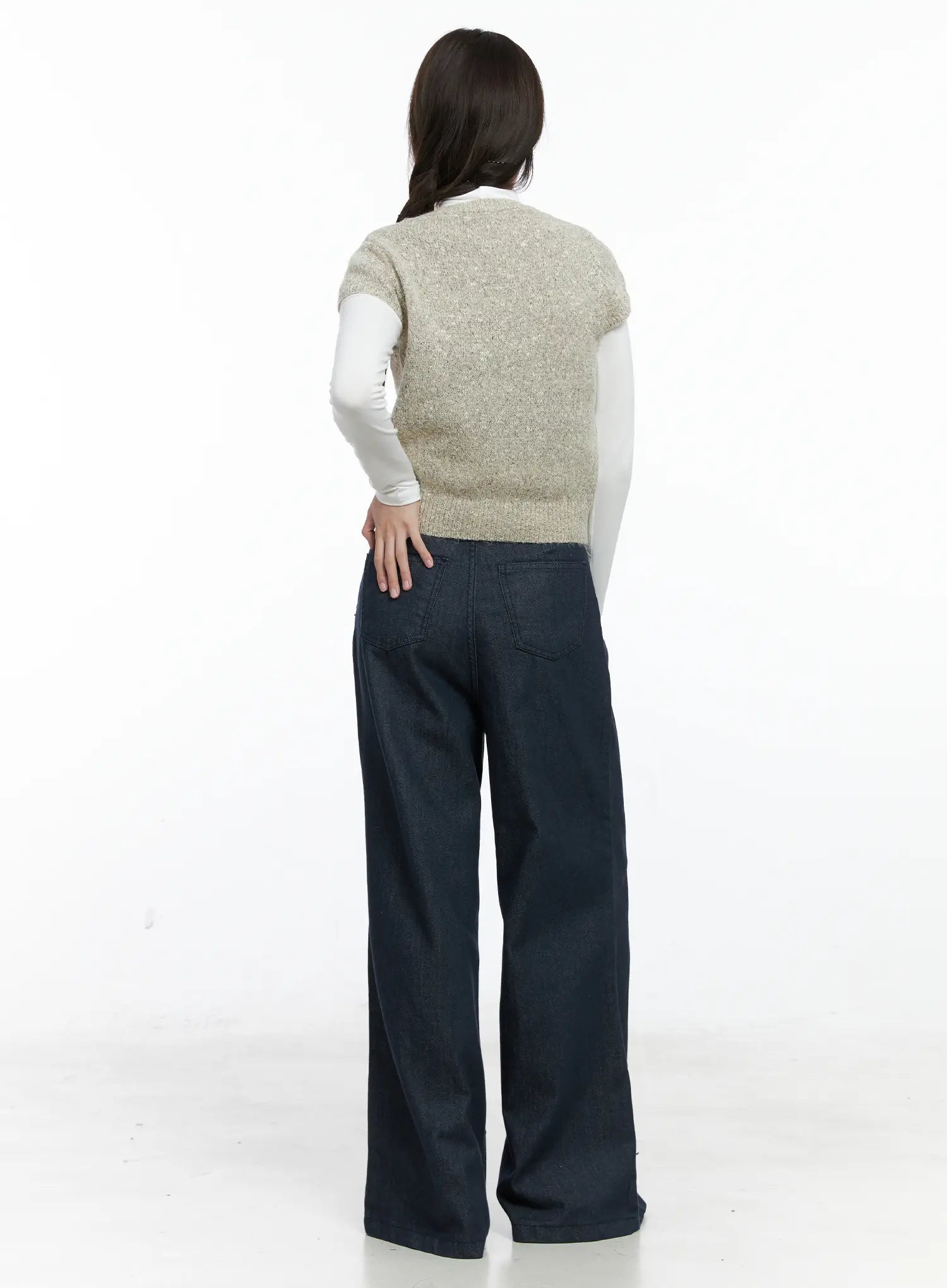 Lena Pintuck Baggy Jeans CO503 in dark blue, direct back view on model, highlighting dual back patch pockets and wide-leg silhouette, paired with beige knit vest and white turtleneck.