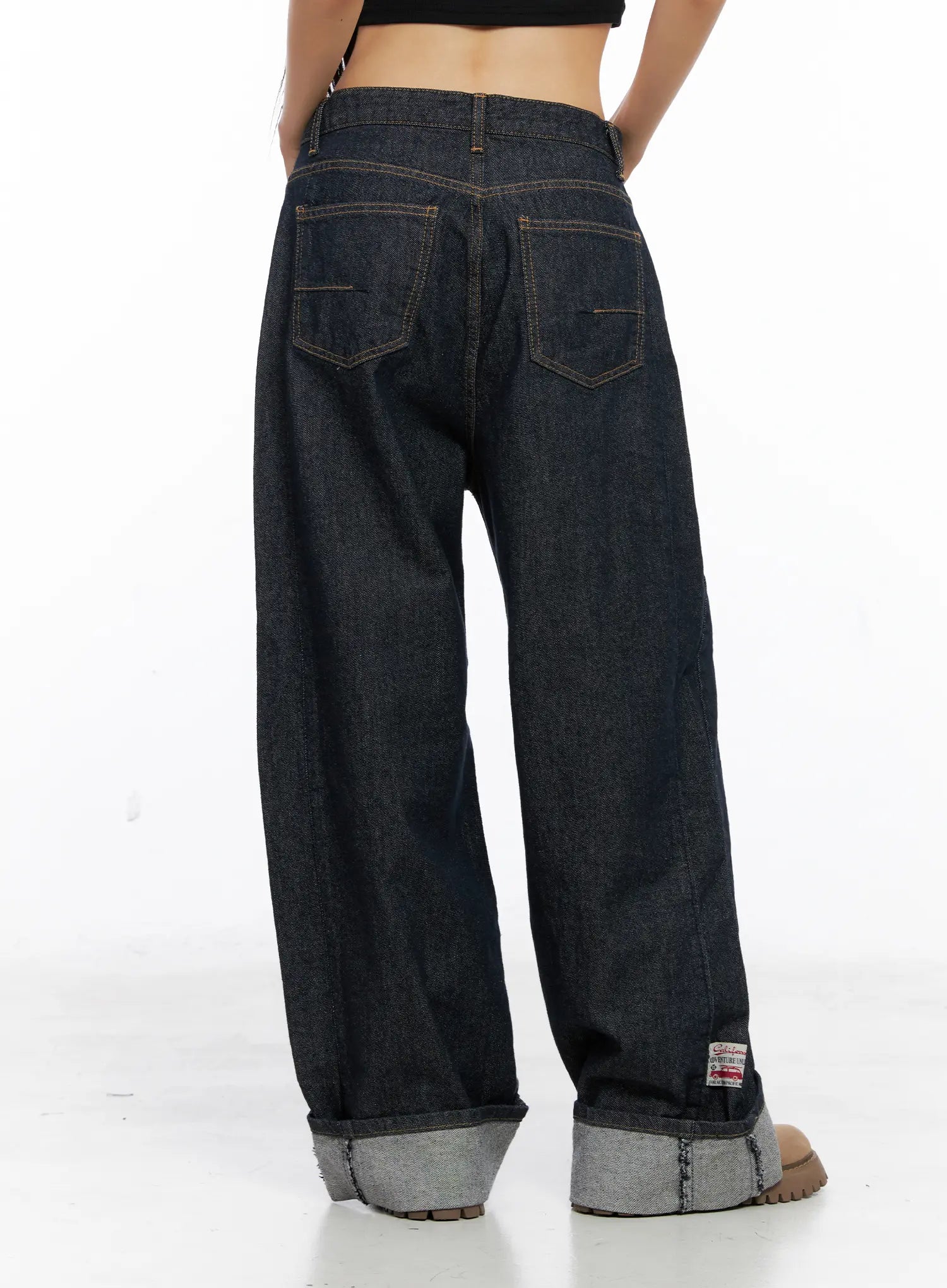 Oakley Cuffed Wide-Leg Jeans CS511 in dark blue, back view on model, dual back pockets with contrast stitching, wide-leg fit, contrast grey roll-up cuff, and woven label at hem.