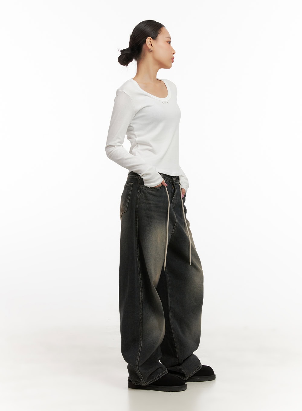 Matilda Washed Denim String Baggy Jeans CD410 in black, full-body side on model looking left, oversized baggy leg pooling at hem, cream drawstrings visible, styled with white fitted long-sleeve top.