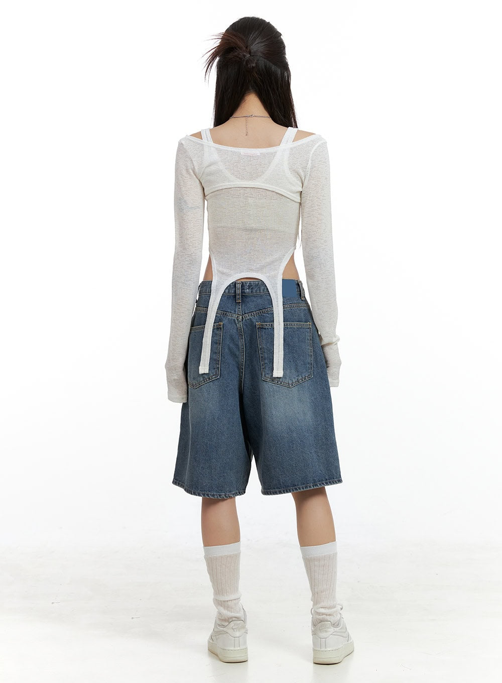 Low Rise Bermuda Jorts CL424 in blue, back view on model, wide-leg washed denim with dual back pockets and faded wash detail, low rise waist, paired with white layered top and sneakers.