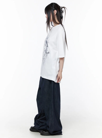 Casual Graphic Short Sleeve Top CU519 in White, full-body side view on model, showing oversized length and relaxed drop-shoulder fit, paired with wide-leg dark denim and black loafers.