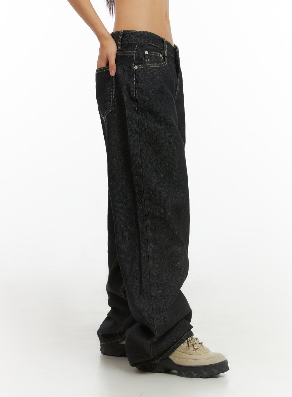 Clover Stitched Baggy Jeans IS402 in black, side close-up on model from waist to hem, showing low-rise waistband, contrast stitching, and extra-wide leg pooling over chunky boots.