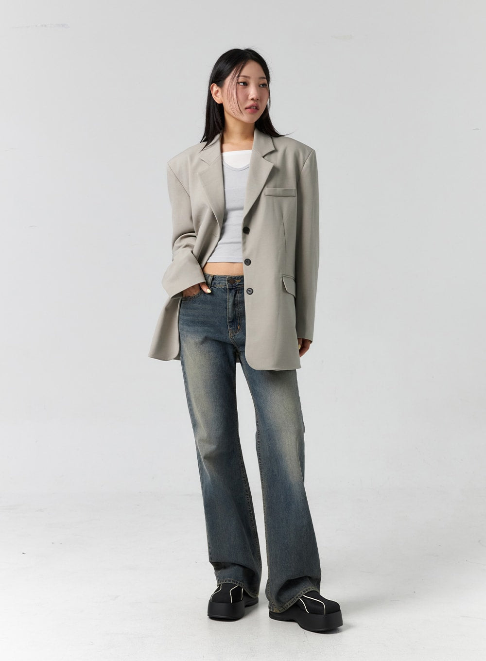 Vintage Wash Bootcut Jeans CS305 in blue, three-quarter front angle on model, highlighting bootcut silhouette and worn-in wash, styled with beige blazer and white crop top.