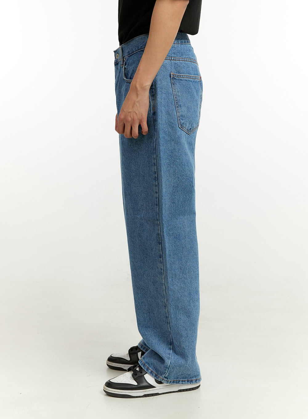 Men's Wide Fit Jeans IL412 in blue, side view on model, showing straight wide leg and back pocket detail, medium-wash denim, worn with black tee and sneakers.