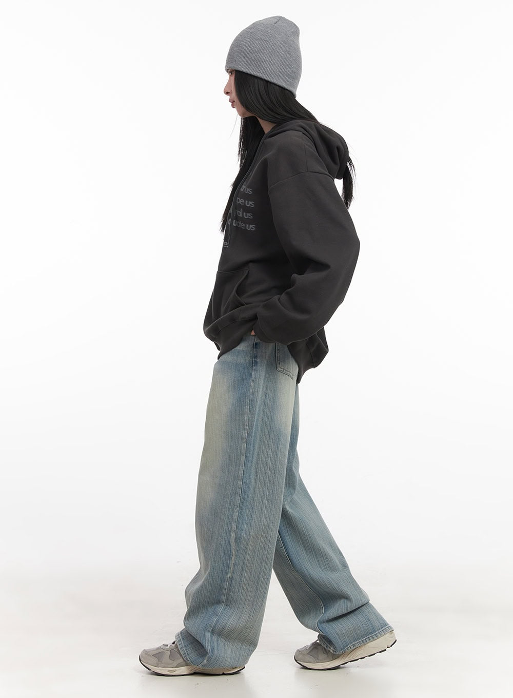 Nicola Washed Wide-Leg Jeans CF514 in light blue, three-quarter side-back walking pose on model, washed denim with elongated wide leg, styled with oversized hoodie and grey beanie.