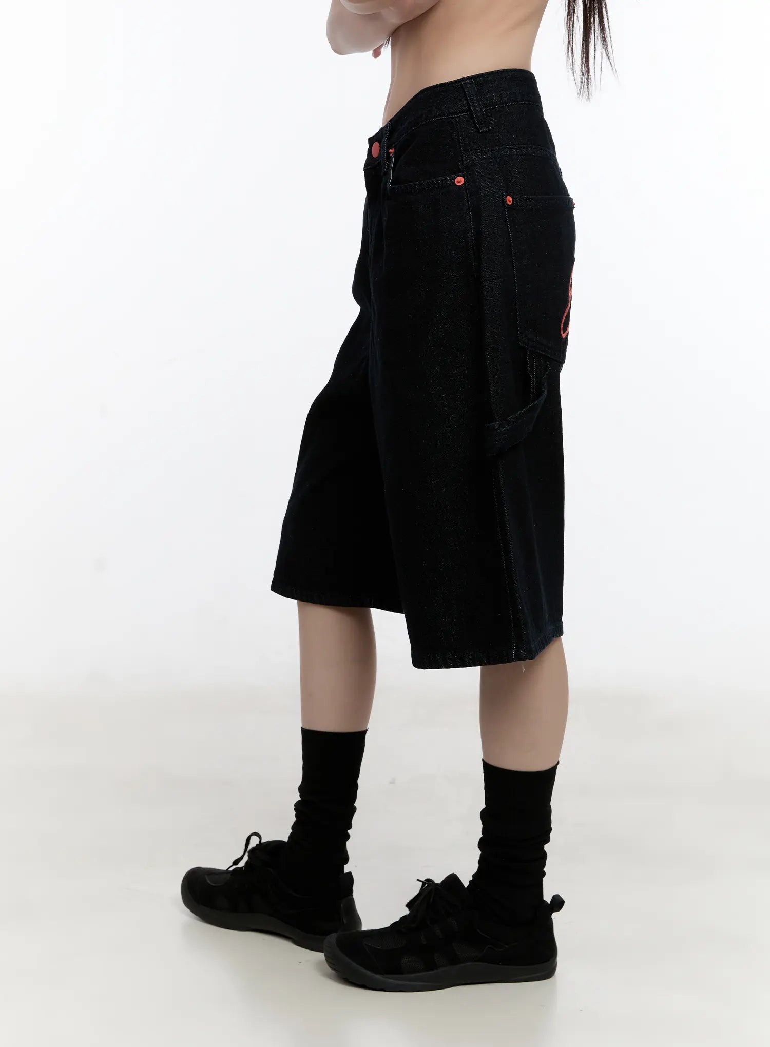Red Text Graphic Embroidered Jorts CL504 in black, close-up side view on model, wide-leg denim silhouette, red script embroidery and cargo-style side pocket detail visible.