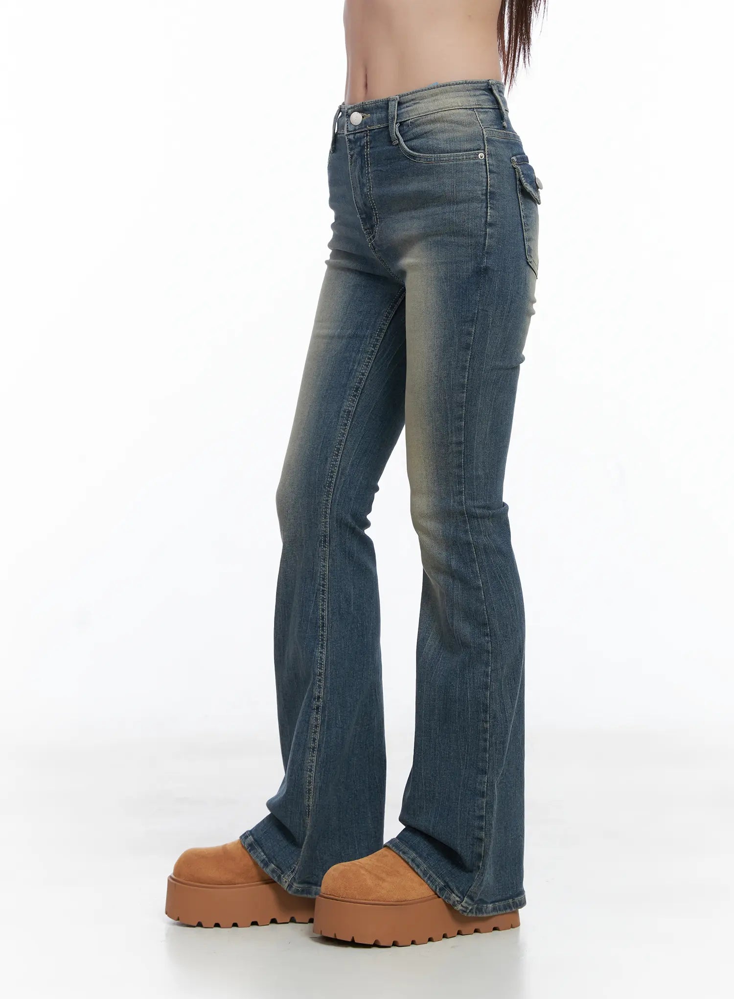 Sloan Vintage Hip Pad Flare Jeans CS502 in dark blue, side view on model, slim thigh tapering to flare hem, vintage wash with yellow tint, side pocket detail visible, chunky platform shoes.