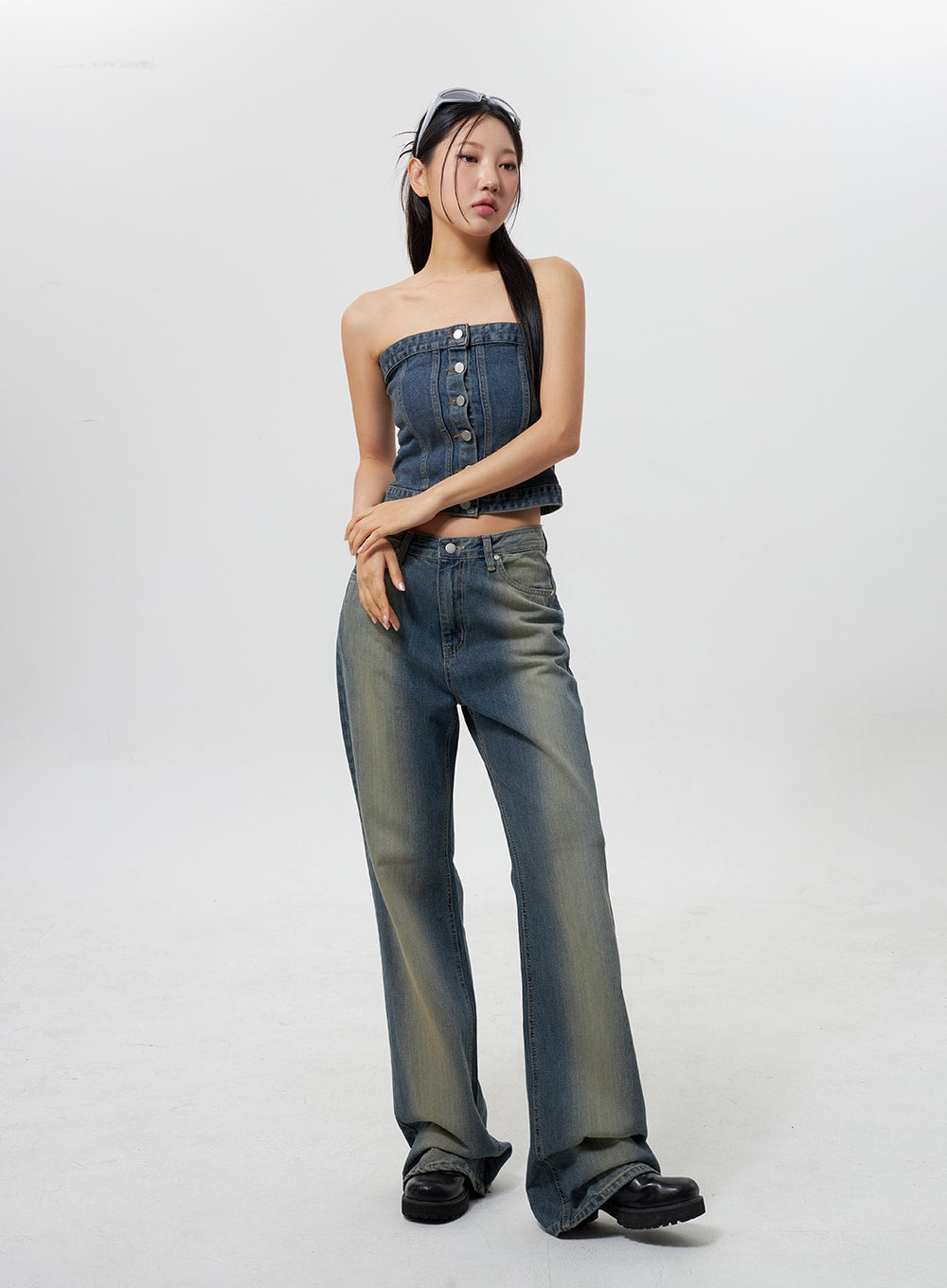 Low Rise Wide Leg Jeans CY323 in vintage blue, three-quarter front view on model with slight turn, low-rise wide-leg cut, distressed yellow fade wash, paired with denim strapless crop top and black platform boots.