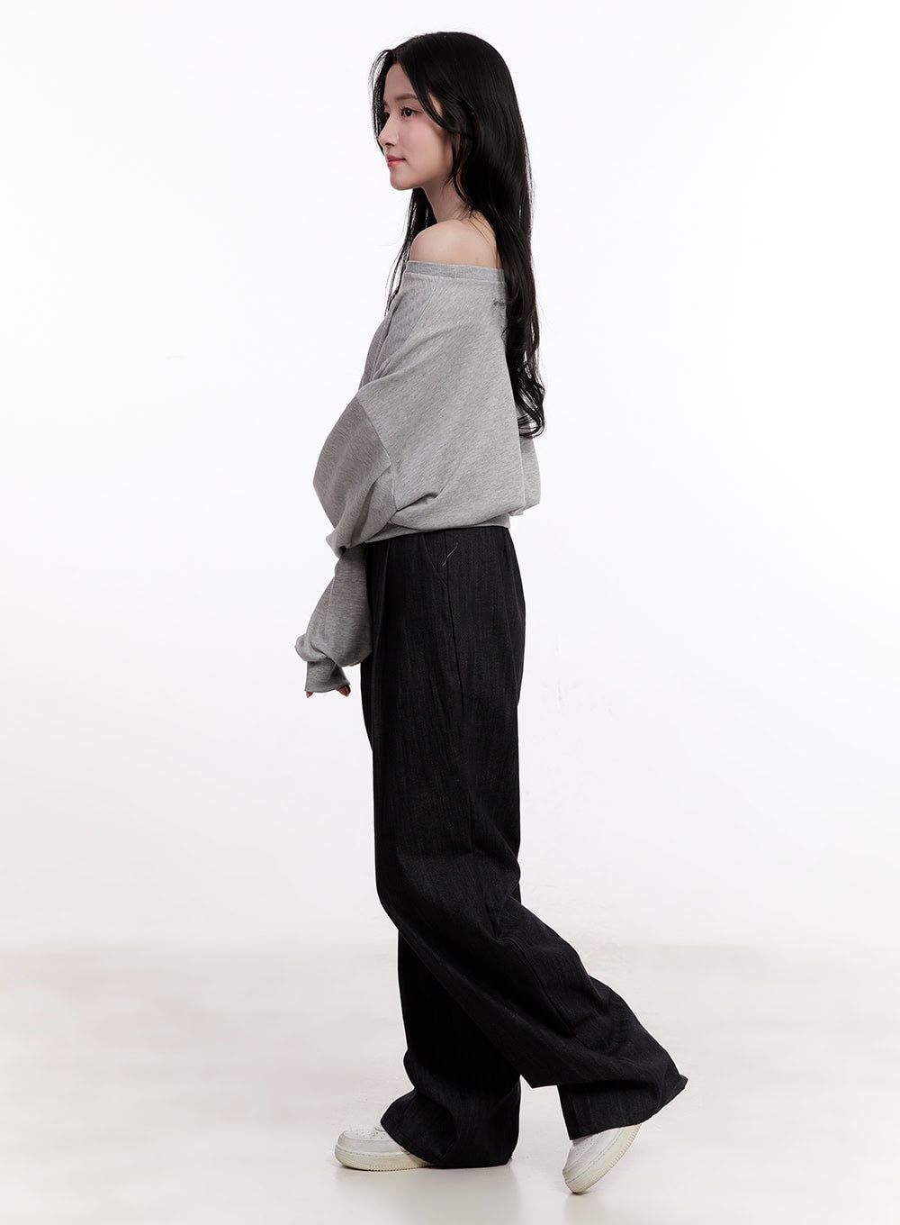 Pintuck Wide-Leg Denim Pants CM527 in black, side profile on model walking, wide-leg denim drape visible, styled with grey off-shoulder top and white sneakers.