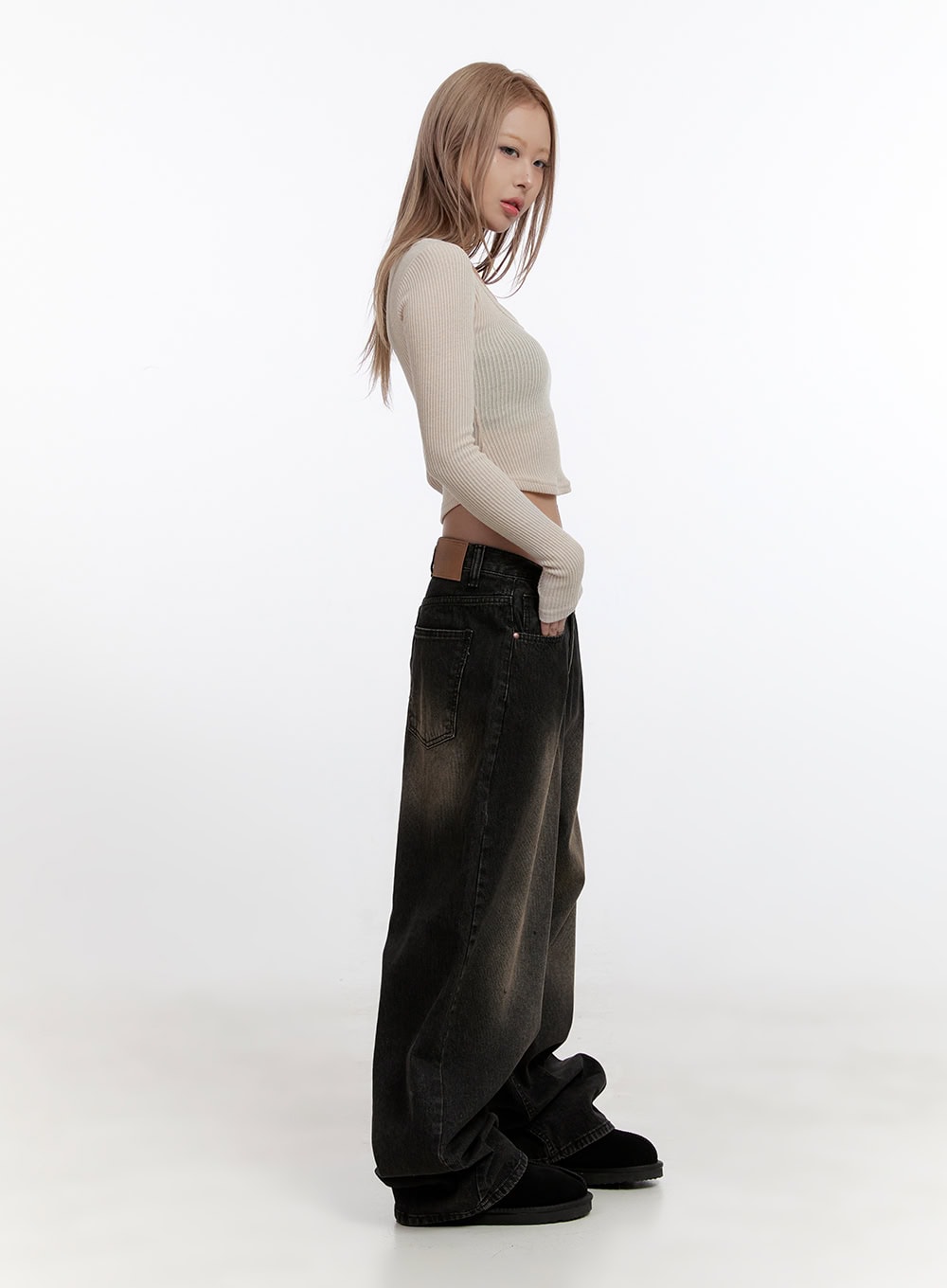 Sabina Low Waist Wide Fit Denim Jeans CN425 in Black, full-body side profile on model glancing back, low-rise waist and voluminous wide leg visible, styled with cream ribbed crop top and fluffy slides.