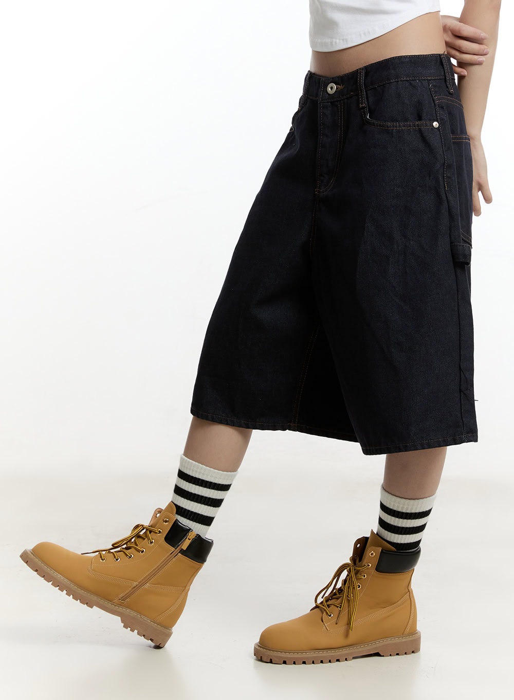Carpenter Denim Wide-Leg Jorts CY501 in dark blue, side close-up on model in motion, wide-leg midi denim with carpenter pocket detail and contrast stitching, with striped socks and tan boots.