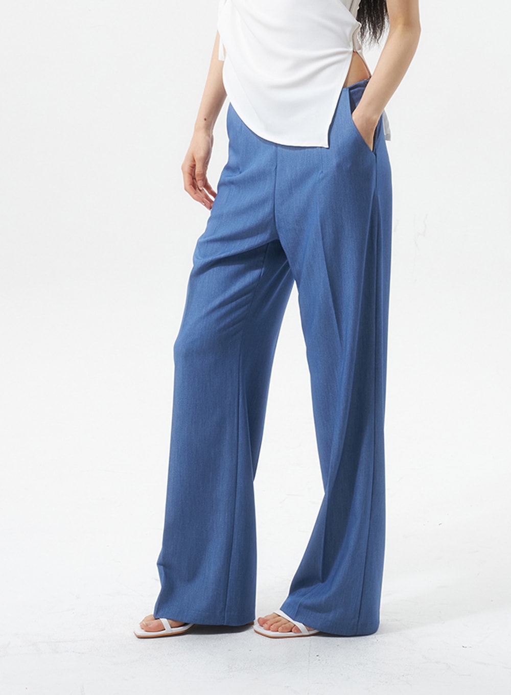 Low Rise Tailored Pants IU326 in blue, side close-up on model, low-rise waist and wide-leg drape shown from hip to hem, hand in pocket, paired with white top.