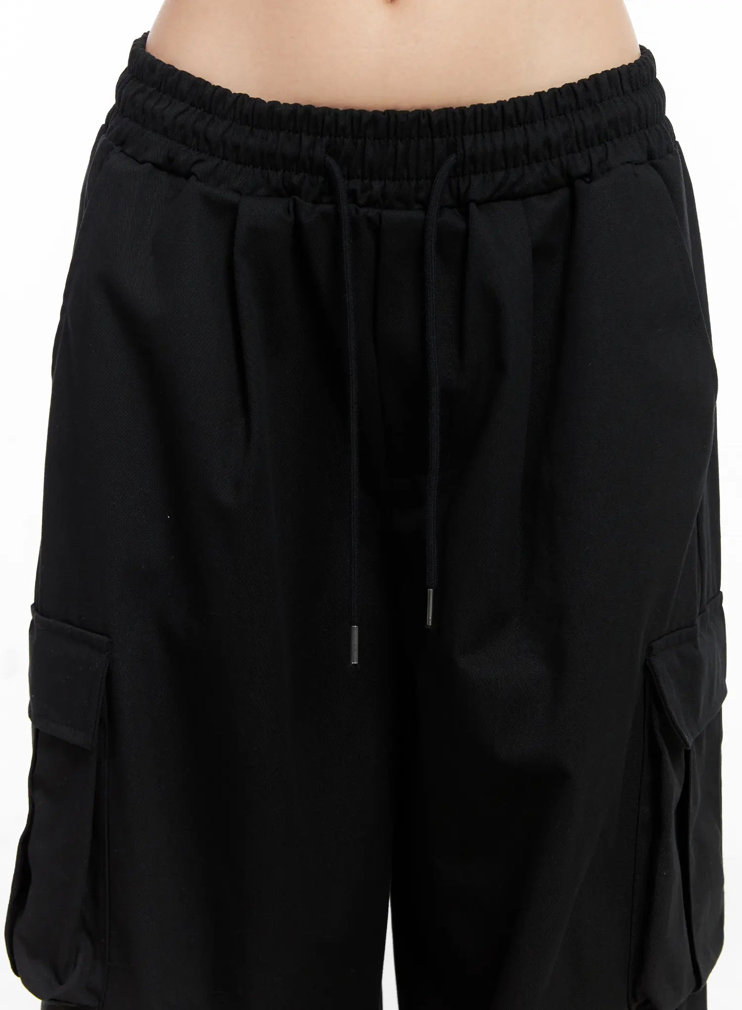Wide Leg Cargo Pants CC1109 in black, waist close-up on model, elasticated ruched waistband with dual drawstring cords, cotton fabric texture, side cargo pocket flaps visible.