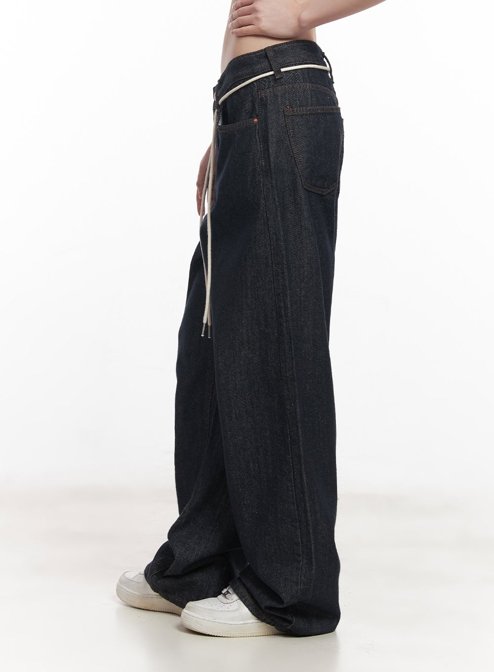 Kirsten String Wide-Leg Summer Denim Jeans IM528 in dark blue, side close-up view, showcasing raw denim texture, cream string detail at hip, wide-leg volume and hem pooling near sneakers.