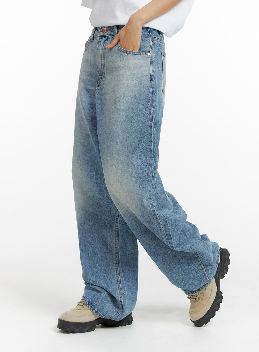 Washed Wide-Leg Jeans CF419 in blue, side close-up on model, wide-leg cotton denim with natural whisker fading, hand in pocket, pooling slightly at chunky sneakers hem.