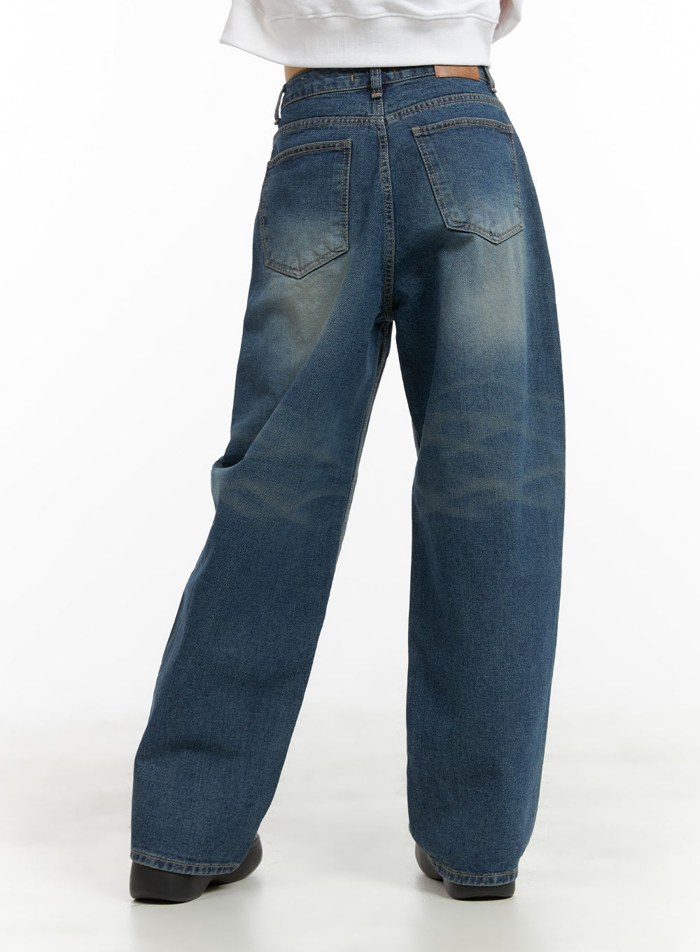 Washed Wide Leg Jeans CA419 in blue, back view on model, two back patch pockets with washed fading detail, wide-fit cotton denim, paired with white cropped top.