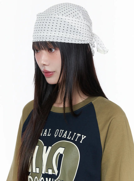 Polka Dot Head Scarf CU519 in White, three-quarter close-up on model, side-knot tie detail visible, black polka dot print on white fabric, worn with raglan graphic tee.