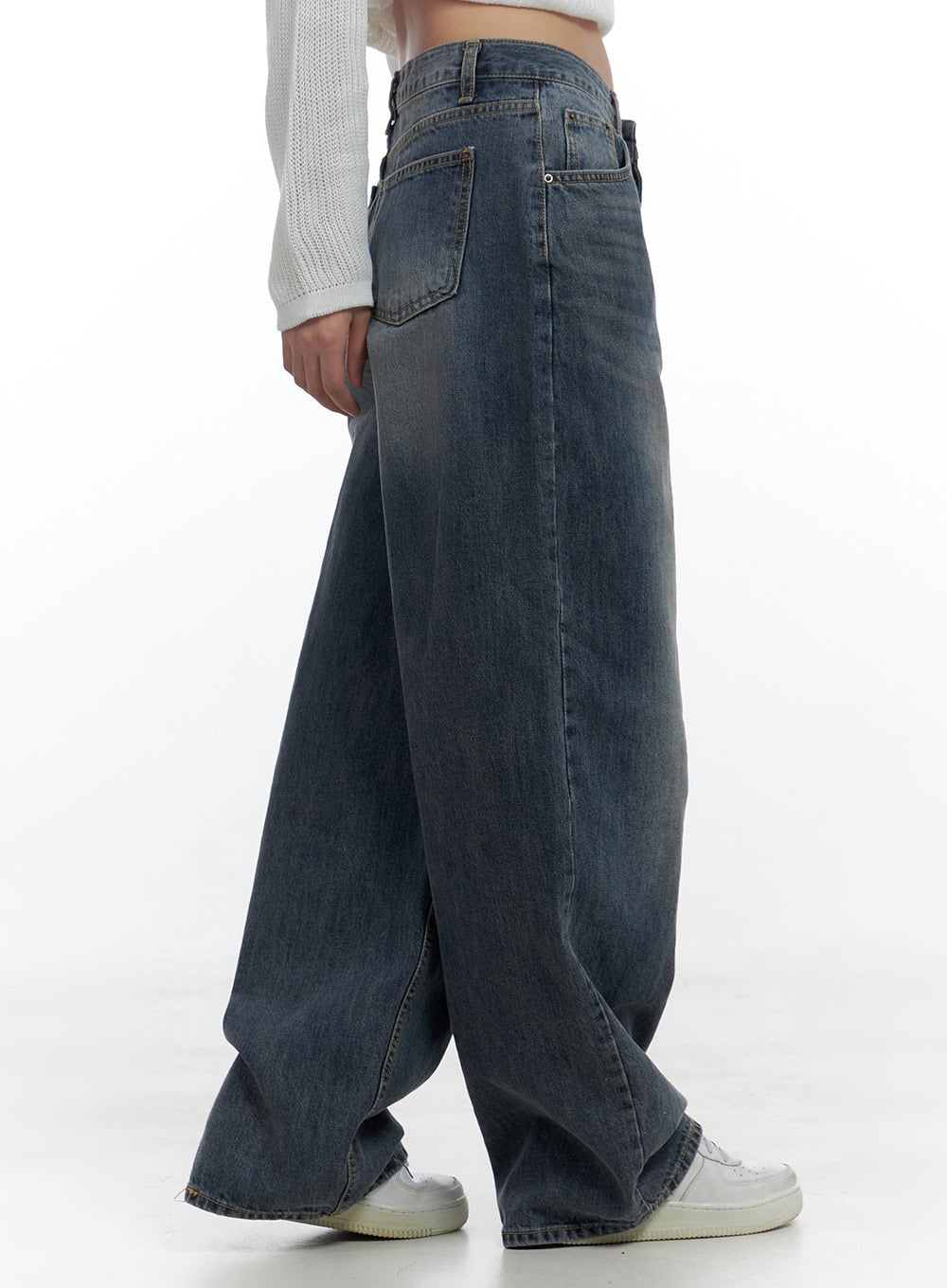 Lana Oversized Wide-Leg Jeans CS425 in blue, side close-up from waist down on model, washed denim highlights back pocket, low-rise waistband, and sweeping wide leg, with white crop knit top.
