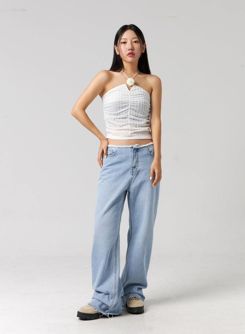 Cut Waist Wide Leg Jeans CG323 in light blue, full-body front shot on model, relaxed wide-leg silhouette with frayed cut waist, one hand on hip, paired with white halter crop top.
