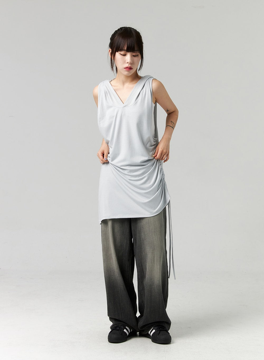 Baggy Jeans CL321 in washed dark grey, full-body front view on model looking down, wide-fit gradient denim with voluminous leg, styled with grey ruched tank and black sneakers.