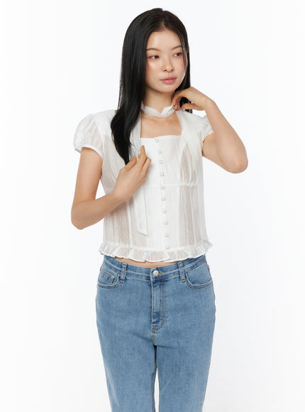 Puff Sleeve Shirred Blouse with Scarf IU519 in white, front close-up on model adjusting scarf, square neckline and button-front detail highlighted, sheer fabric with shirring, paired with blue jeans.