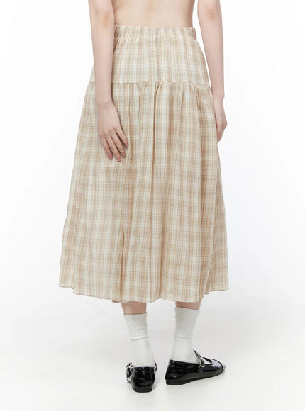 Plaid Flare Maxi Skirt CU519 in beige, back view on model standing straight, revealing tiered gather seam and flared hem, elastic waist detail, lightweight plaid fabric, styled with white socks and black Mary Janes.