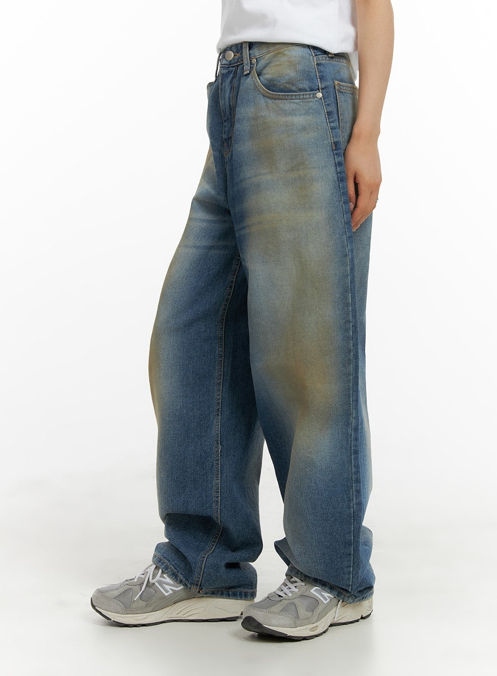 Vintage Washed Baggy Jeans CM426 in blue, side view on model, wide-fit denim with bold vintage yellow wash along thigh and hip, pooling slightly at grey sneakers.