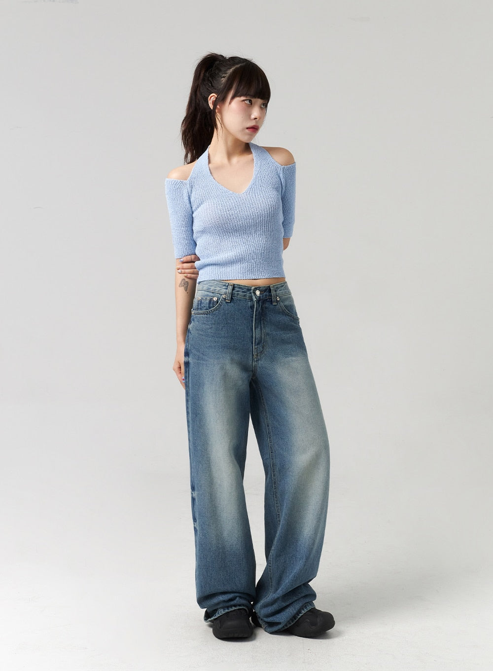 Mid-Wash Baggy Jeans CL312 in mid-wash blue, angled full-body view on model, relaxed wide leg with faded thigh wash, worn with blue cold-shoulder ribbed knit top.