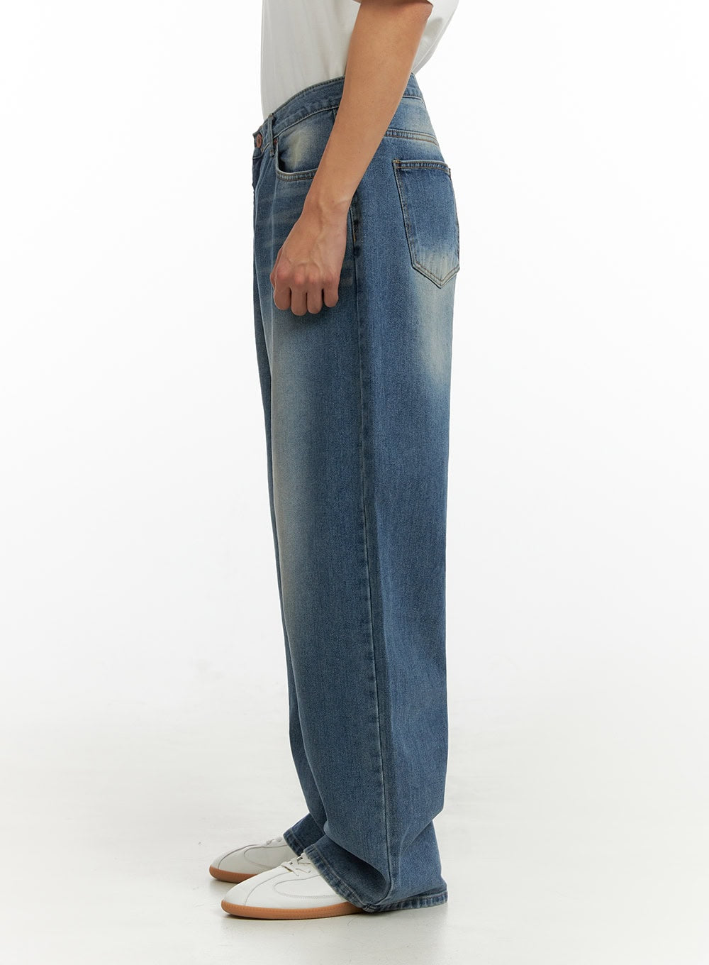 Men's Solid Baggy Jeans IU419 in blue, side view on model, showing wide-leg silhouette, washed denim with faded seam line and back patch pocket, paired with white tee.