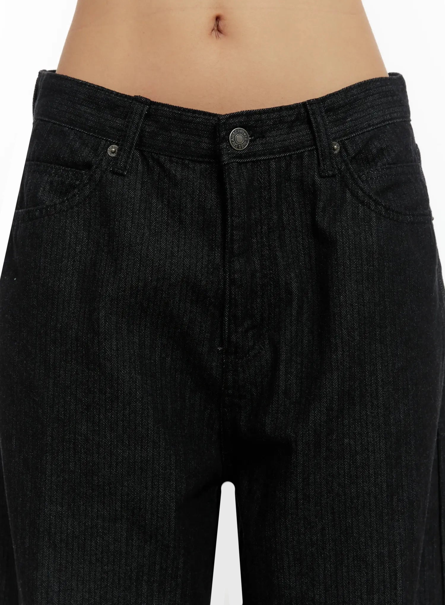Amyra Baggy Striped Jeans ID525 in black, close-up detail of waistband and front pockets on model, low-rise fit with metal button closure and subtle vertical stripe cotton denim.