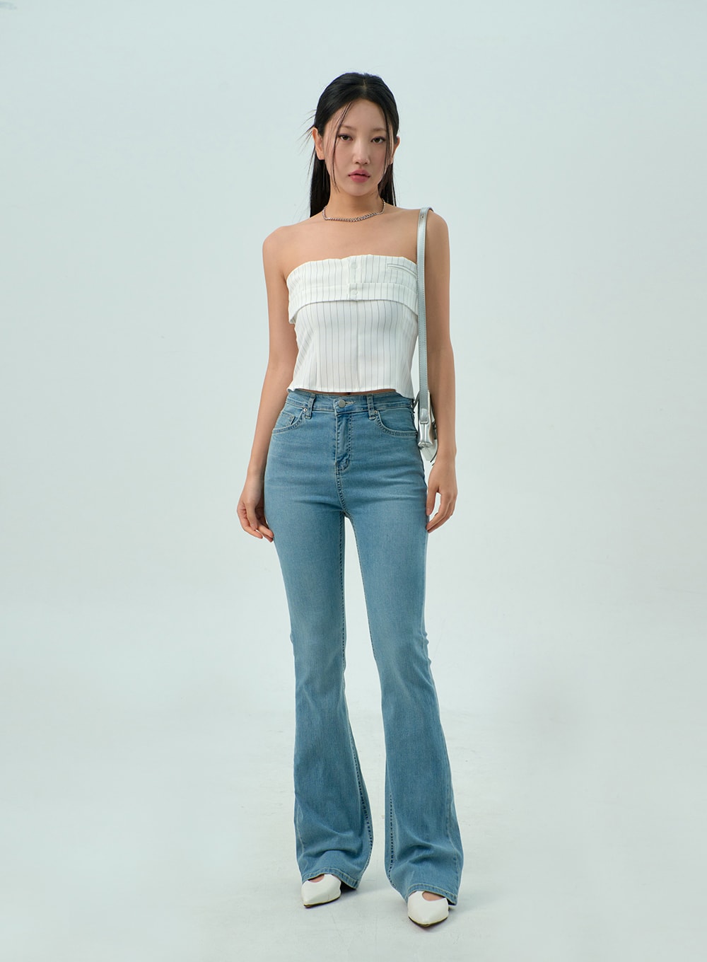 Light Wash Bootcut Jeans CY330 in light blue, slight angle front view on model, high-rise slim fit with subtle washed finish and flared bootcut leg, paired with white tube top and bag.