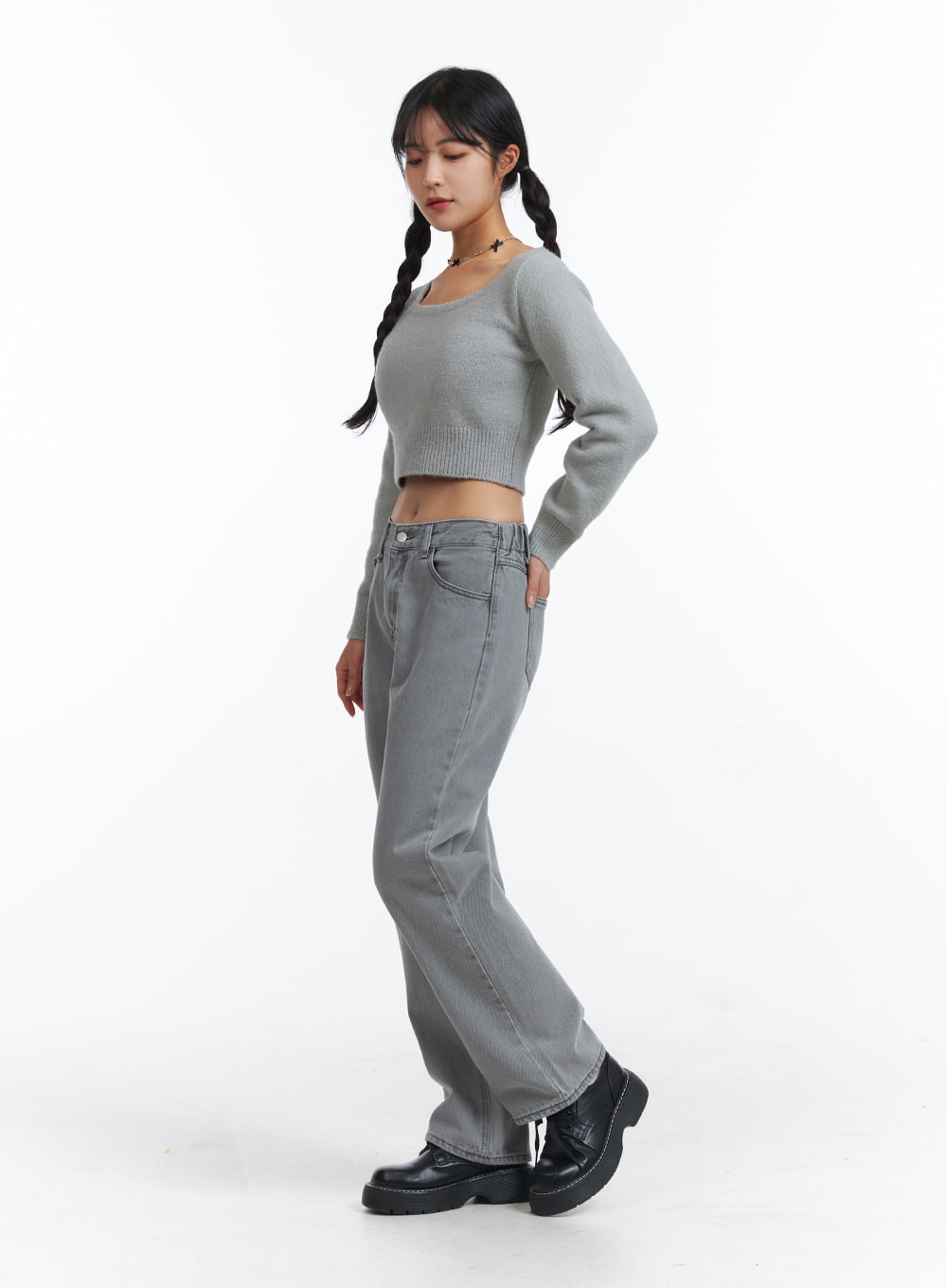Low-Rise Straight Leg Jeans OJ426 in gray, three-quarter side view on model looking down, wide-fit low-rise washed denim, styled with crop knit sweater and chunky black boots.