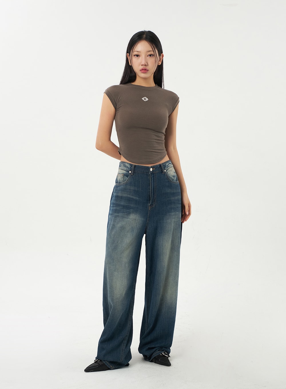 Baggy Low Rise Jeans CA326 in dark blue, straight-on front full-body shot on model, low-rise waistband with silver rivets, wide-leg denim with yellow-tinted fading at thighs.
