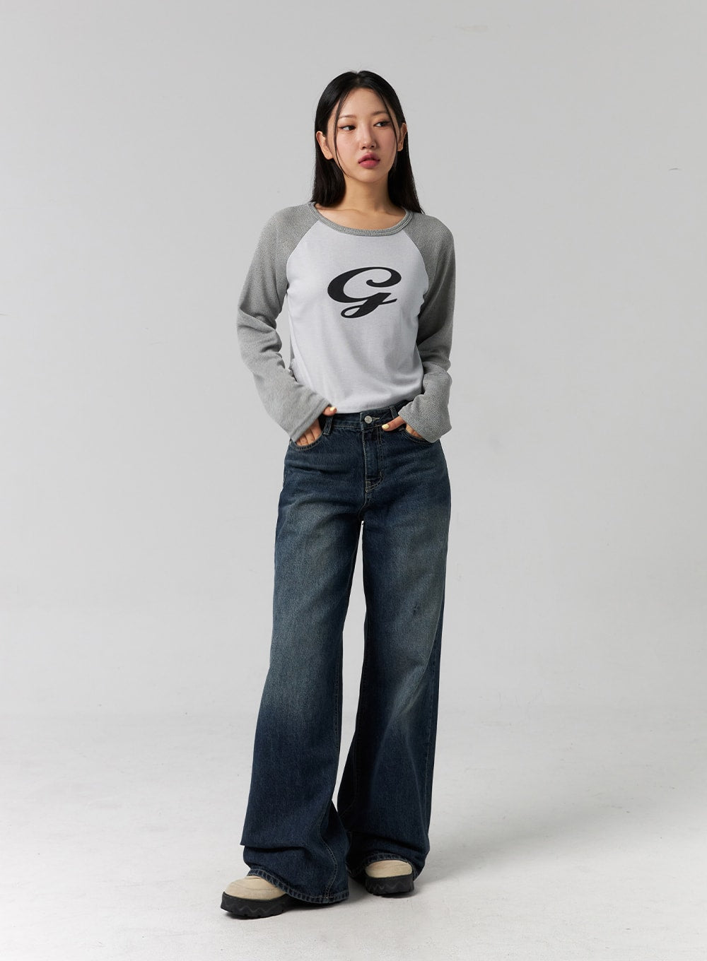 Low Rise Washed Wide Jeans CG315 in dark blue, full-body front shot on model with hands in pockets, casual relaxed pose, wide-leg washed denim, paired with grey raglan crop top.