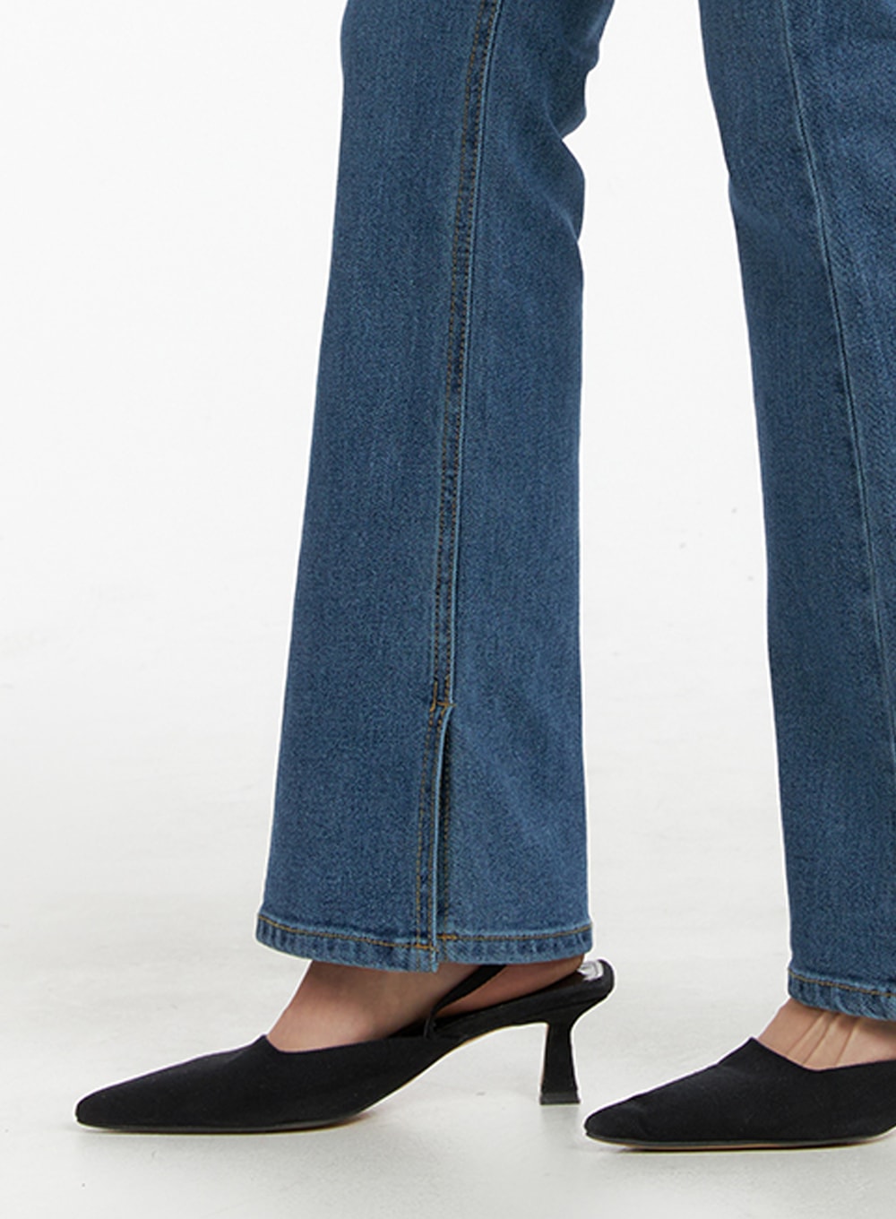 Vintage Flared Jeans IM414 in blue, close-up detail of hem and flare on model, showing bootcut slit hem and stitching, worn with black slingback kitten heels.