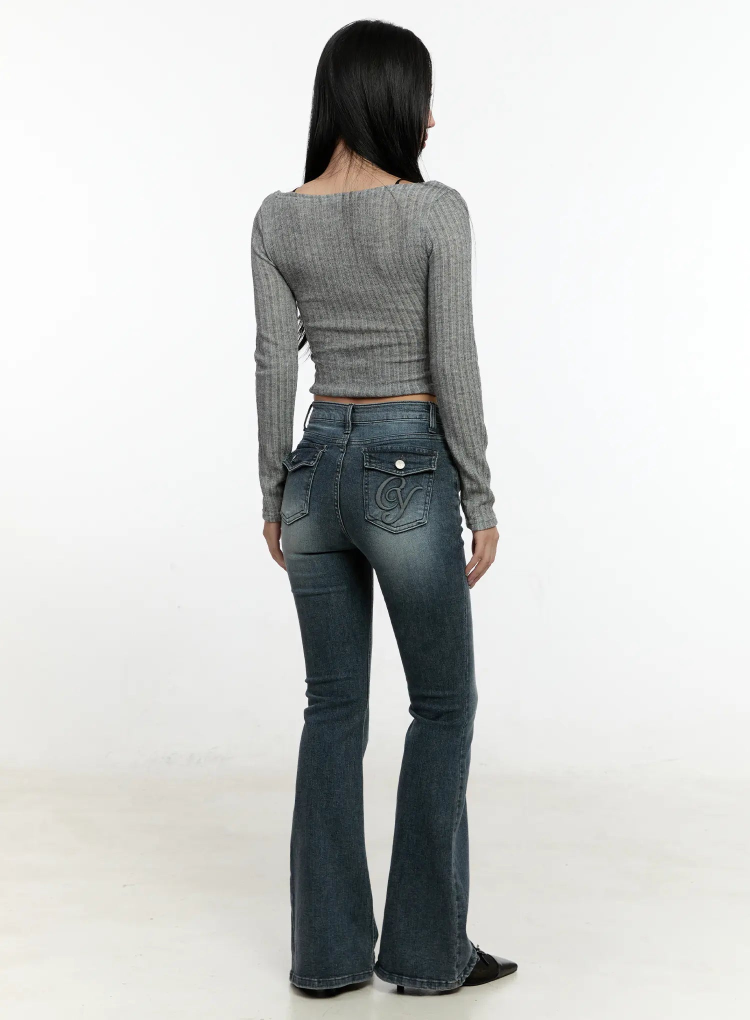Marley Hip-Pad Denim Bootcut Jeans CN506 in dark blue, back view on model, embroidered logo back pocket and snap-button flap shown, styled with grey ribbed crop top and black heels.