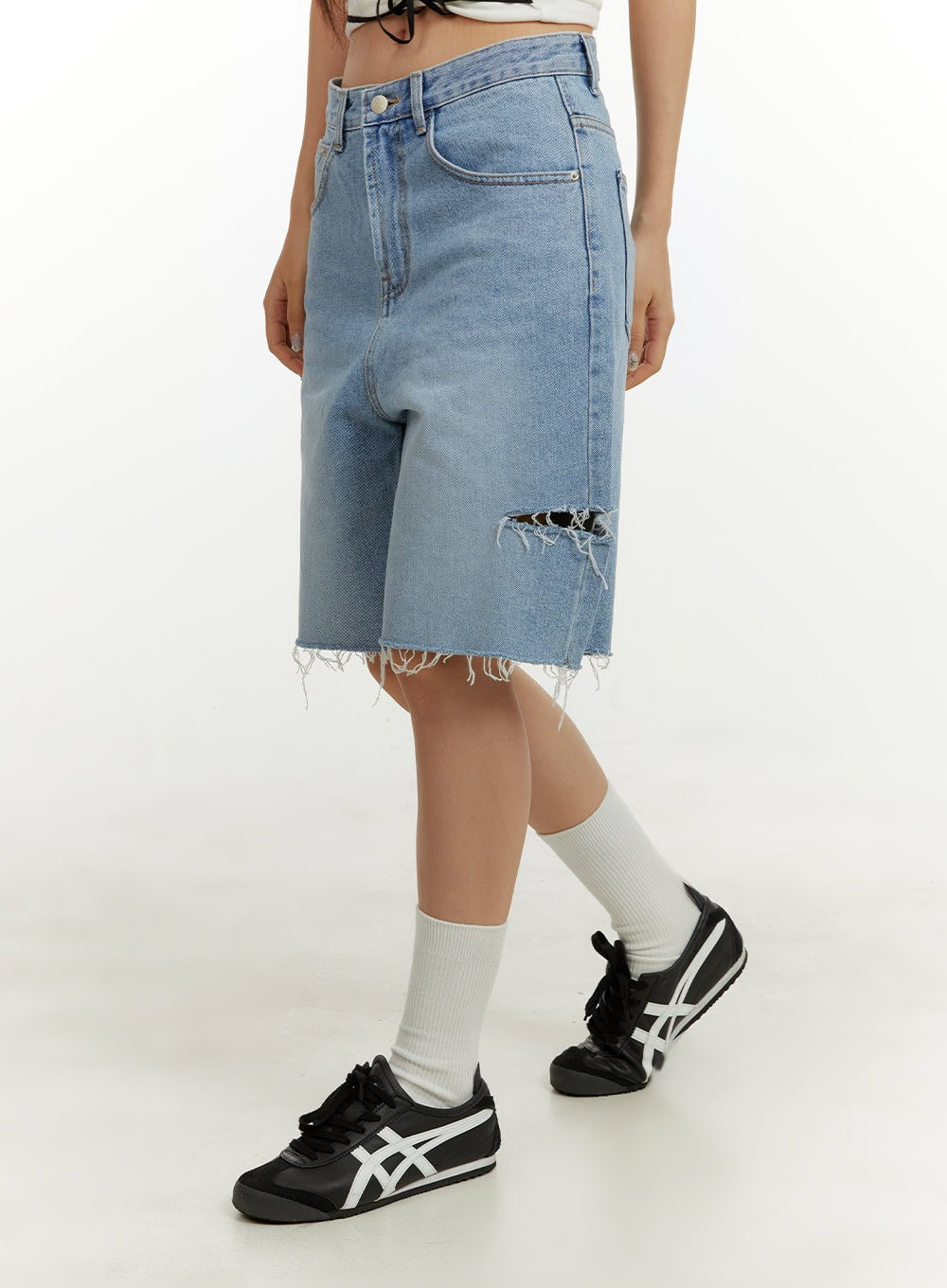 Straight Leg Jorts CY408 in blue, side view on model, wide-fit washed denim with ripped thigh hole and frayed hem, paired with white socks and black sneakers.