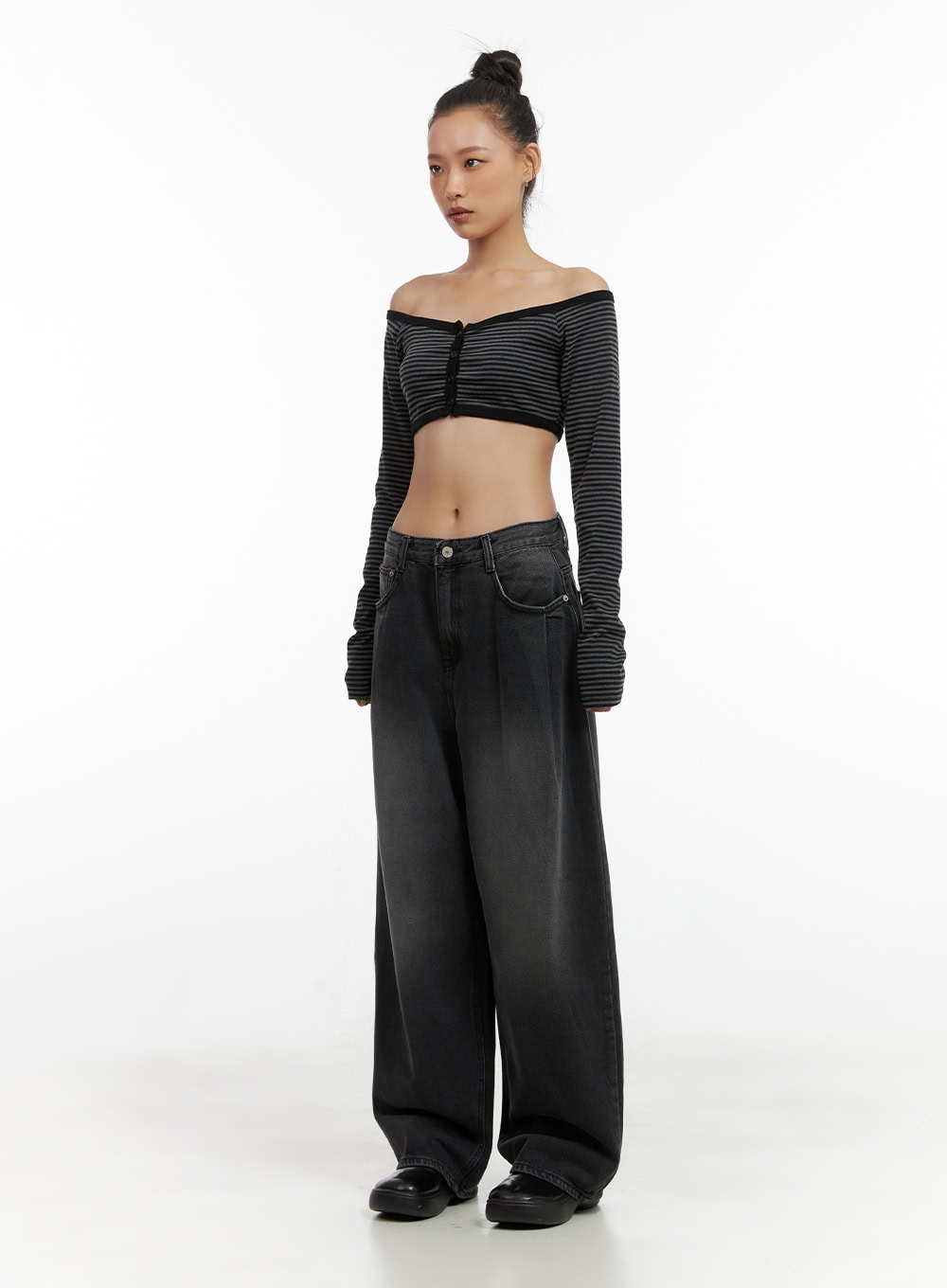 Delilah Pin-Tuck Washed Denim Baggy Jeans CO424 in black, front three-quarter view on model, low-rise waistband and pintuck front crease visible, styled with striped off-shoulder crop top.
