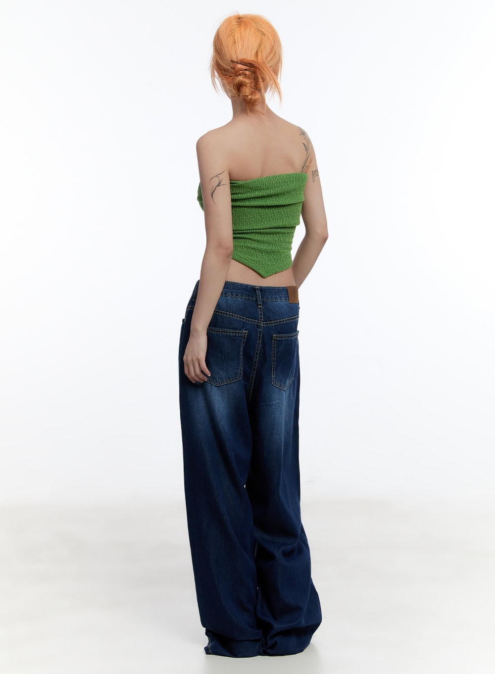 Jill Baggy Jeans CY530 in dark blue, back full-body view on model, revealing large back pockets and washed fading detail, paired with green knit bandeau and beige sandals.