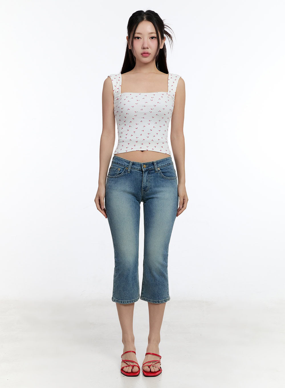Kyra Cropped Low-Rise Skinny Jeans IU503 in blue, full-body front on model standing straight, washed skinny crop silhouette, paired with white cherry print tank and red heeled mules.