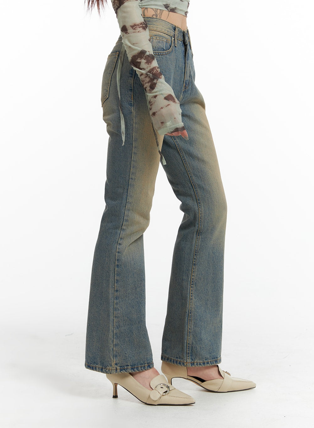 Washed Flared Jeans IF426 in blue, side view on model with one leg raised, slim-fit flared leg and washed cotton denim texture visible, paired with mesh crop top.