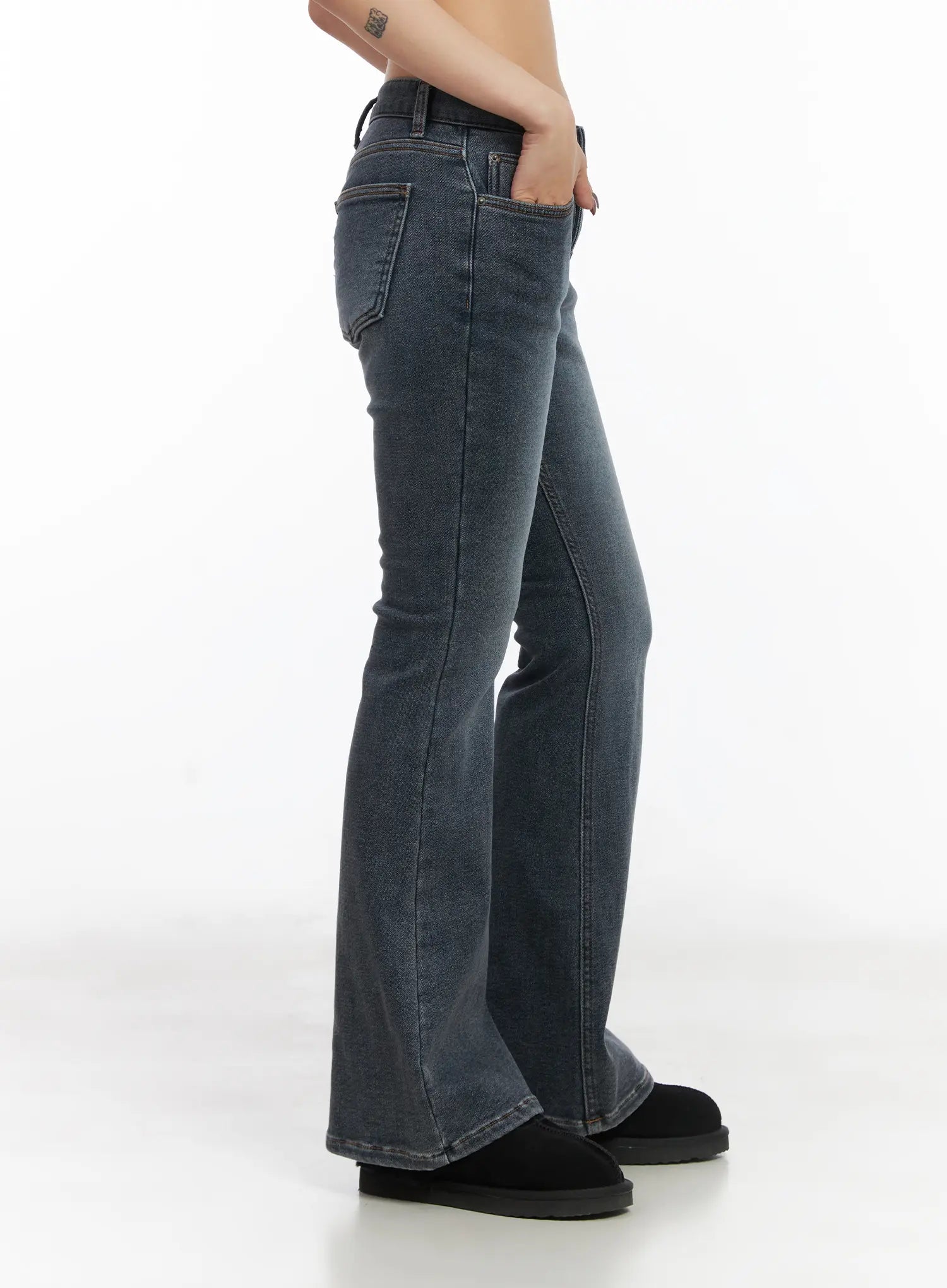 Kiera Low-Rise Fleece-Lined Bootcut Jeans CD509 in washed dark blue, side view on model, low-rise waist with front pocket, slim thigh to flared bootcut leg, worn with black shearling boots.